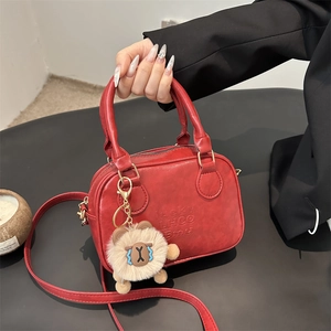 Sac à main vintage en cuir rouge vif avec poignées et un pendentif ours en peluche