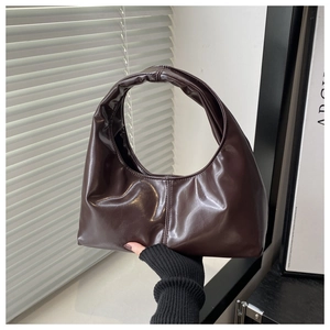 Detailed close-up of dark brown crescent hobo bag in glossy leather with light and shadow
