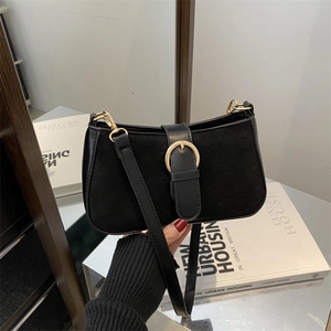 Minimalist black suede and leather patchwork underarm bag with gold buckle detail