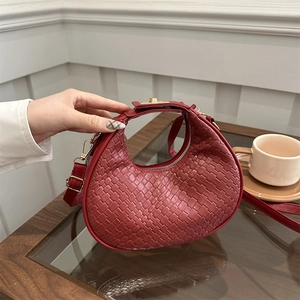 Chic dark red woven crescent handbag with gold hardware and adjustable strap