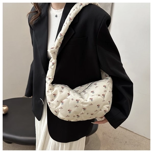 Close-up of quilted beige dumpling bag with floral print and knotted shoulder strap