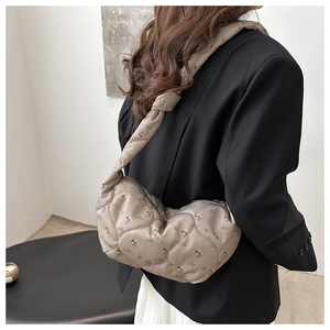 Detail of taupe quilted dumpling bag with floral pattern and knotted shoulder strap