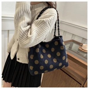Detail of navy knit tote bag featuring brown polka dots and woven black shoulder straps