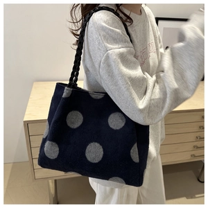 Close-up of soft navy blue polka dot tote bag with black woven shoulder strap detail