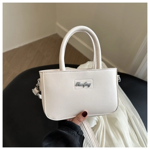 Detail showing white PU leather texture and Shuofeng metal script logo on the handbag