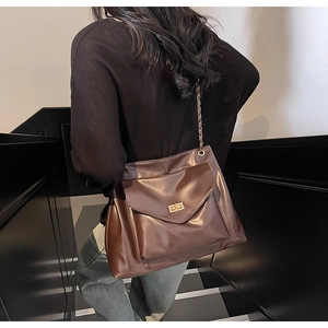 Brown vintage leather crossbody chain bag worn by model on stairs during outdoor shoot
