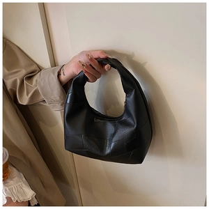 Detail of black leather dumpling bag featuring geometric patchwork and half-moon handle