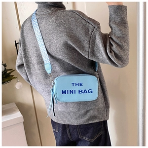 Detail of light blue pebble leather mini bag with geometric wide strap and text logo