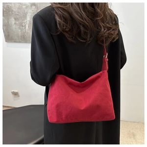 Vista dettagliata di una borsa hobo oversize in camoscio rosso con cappotto nero