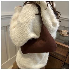 Close-up of brown suede underarm bag on shoulder with triangular geometric profile