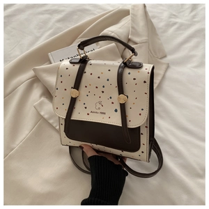 Detailed close-up of cream and brown backpack with dot pattern and gold buckle hardware