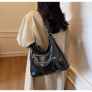 Sac hobo noir brillant chic à trois zips avant porté avec un trench-coat beige élégant