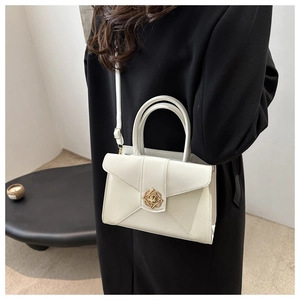 Detail of white leather crossbody bag with golden decorative clasp on black coat