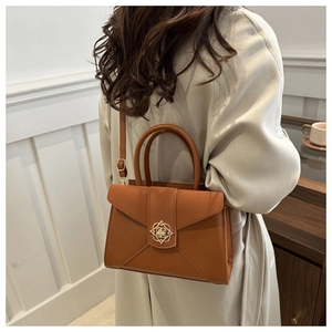 Brown leather handbag with gold flower clasp shown worn on a shoulder strap