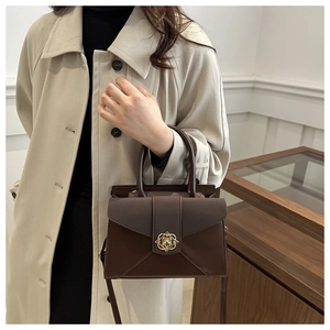 Detail of a vintage dark brown leather handbag featuring an elegant gold floral metal clasp