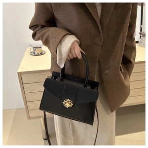 Detail of a structured black crossbody bag with a gold hollow clasp for a chic office look