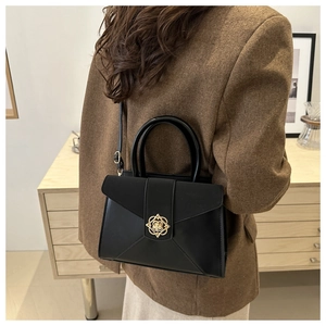 Detail shot of a black leather handbag with an elegant golden floral buckle for daily use