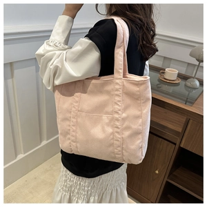 Lifestyle view of light pink corduroy tote bag with wide strap and front pocket