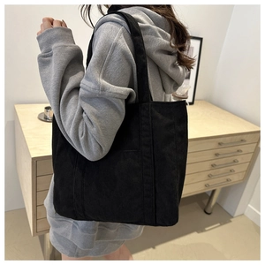 Detailed view of the black corduroy tote bag worn on shoulder for daily casual look
