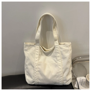 Detail of the minimalist off-white corduroy tote bag showing front pocket and texture