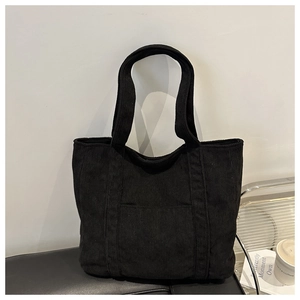 Detail view of the black corduroy tote bag showing its ribbed texture and wide straps