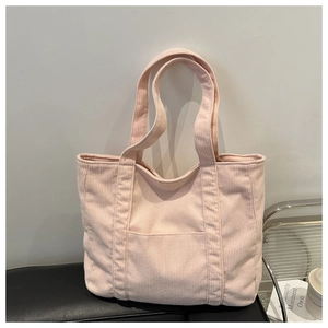 Detail of light pink corduroy tote bag showing the vertical ribbed texture and front pocket
