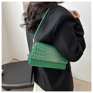 Détail macro du sac à main vert à motif crocodile avec des surpiqûres dorées chic