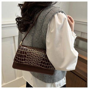 Detail of dark brown baguette bag featuring crocodile texture and golden cracked finish