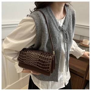 Detailed view of dark brown baguette bag featuring gold-lined crocodile texture on flap