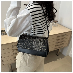 Détail en cuir synthétique noir motif crocodile avec liseré doré sur le sac à bandoulière