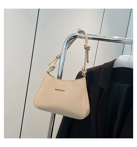 Detail of beige shoulder bag with a unique knotted strap and sleek metal buckle detail