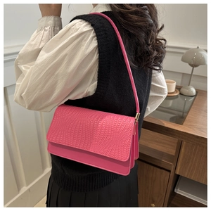 Detailed view of magenta woven shoulder bag with intricate textured flap and slim strap