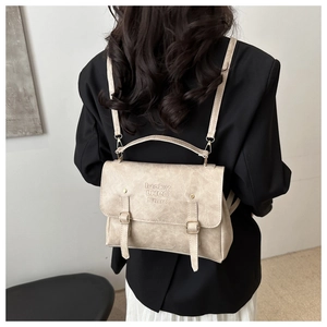 Dettaglio di zaino vintage beige con doppie fibbie metalliche e trama goffrata