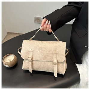 Dettaglio della borsa beige in pelle testurizzata con doppie fibbie e logo inciso