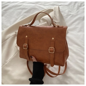 Dettaglio di borsa vintage marrone con doppie fibbie in metallo e scritte a rilievo