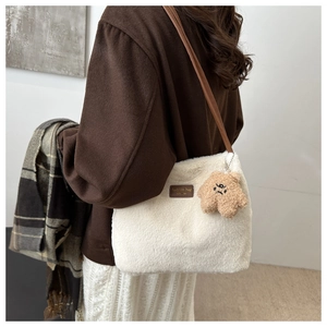 Détail du sac seau en peluche blanche avec bandoulière en cuir brun et breloque ours