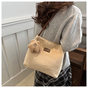 Détail du sac cabas en peluche beige avec écusson en cuir et breloque étoile mignonne