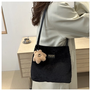 Detail of black plush shoulder bag with gold text label and cute star charm
