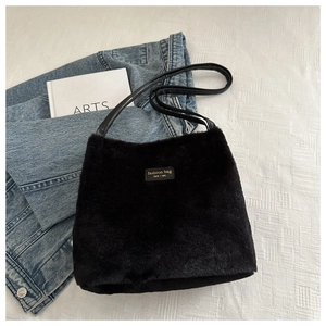 Détail du sac seau noir en peluche avec écusson en cuir sur veste en jean