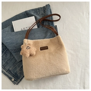 Détail du sac seau en peluche beige avec poignée en cuir marron et breloque ours mignonne