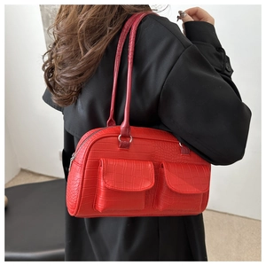 Detail of red crocodile embossed underarm bag with double front pockets on black coat