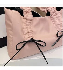 Detailed view of pink tote bag with pleated handles and decorative black bow accents