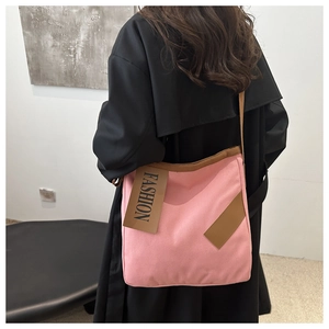 Détail du sac cabas en toile rose avec lanières brunes et étiquette de mode sur manteau