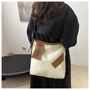 Detail of canvas tote bag with brown leather strap and decorative FASHION tag detail