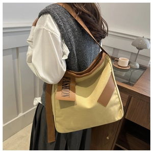 Vue arrière du mannequin portant un cabas en toile jaune avec étiquette en cuir fashion