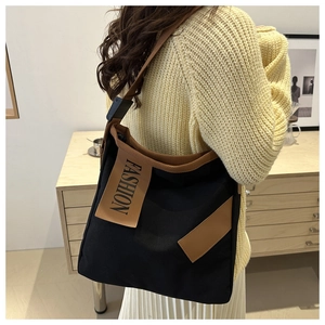Détail du grand sac cabas noir avec étiquette FASHION marron et large bandoulière confortable