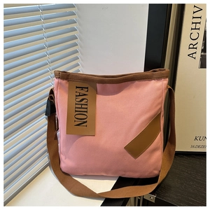 Detail of pink canvas tote with brown woven straps and leather fashion label
