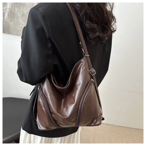 Macro shot of dark brown soft leather texture and silver zipper detail on tote bag