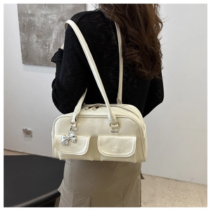 Dettaglio della borsa bowling vintage crema con tasche anteriori e ciondolo a fiocco