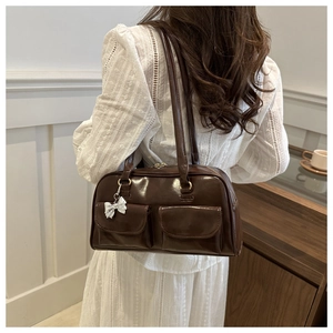 Dettaglio di una borsa bowling vintage marrone scuro con tasche laterali e ciondolo a fiocco